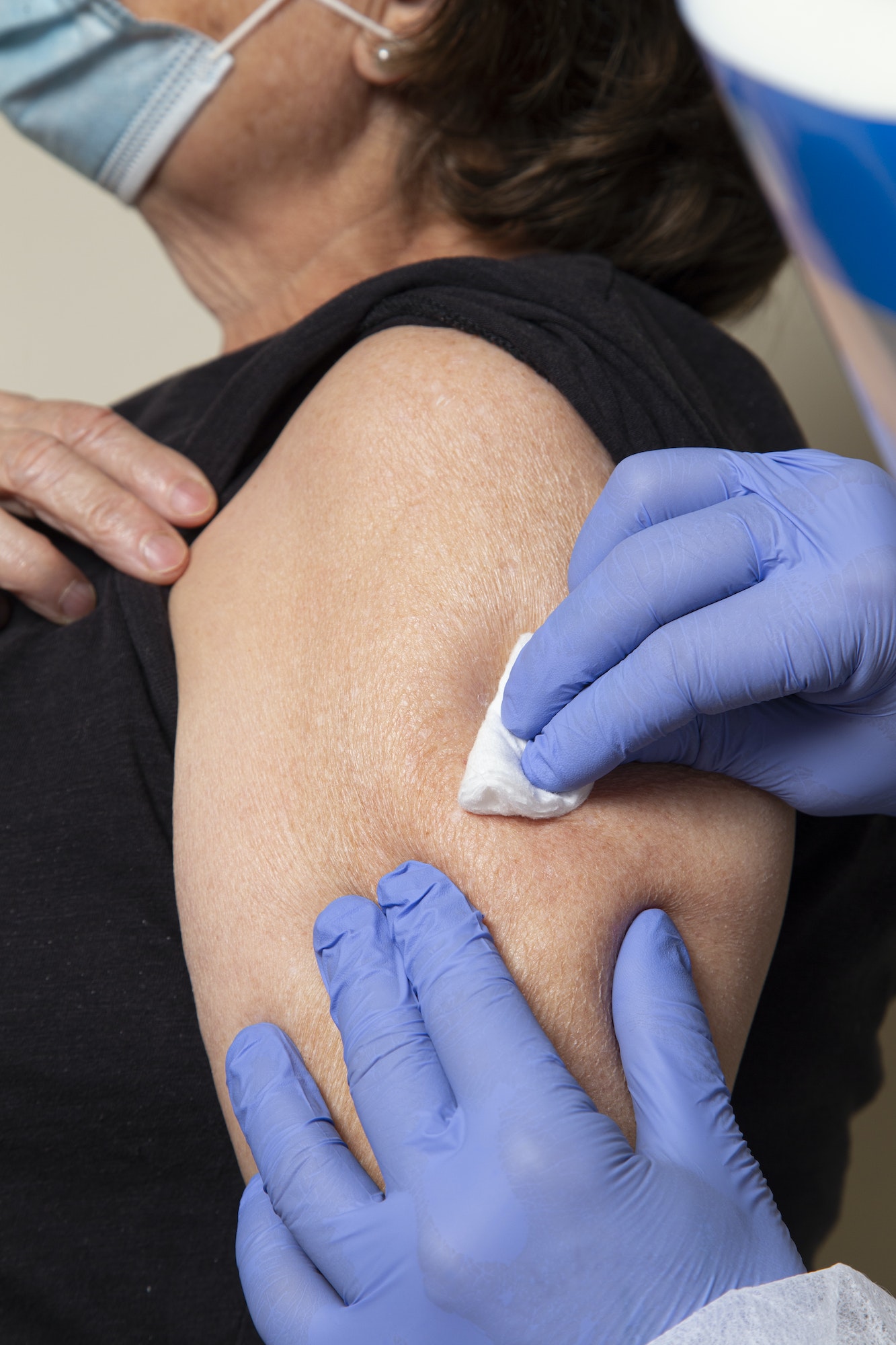 nurse uses alcohol swab on older woman's arm